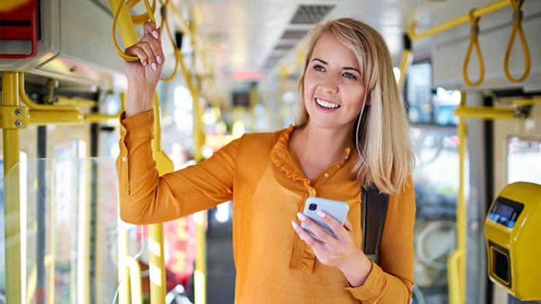 Stehende Frau im Bus mit der Hand am Haltegriff