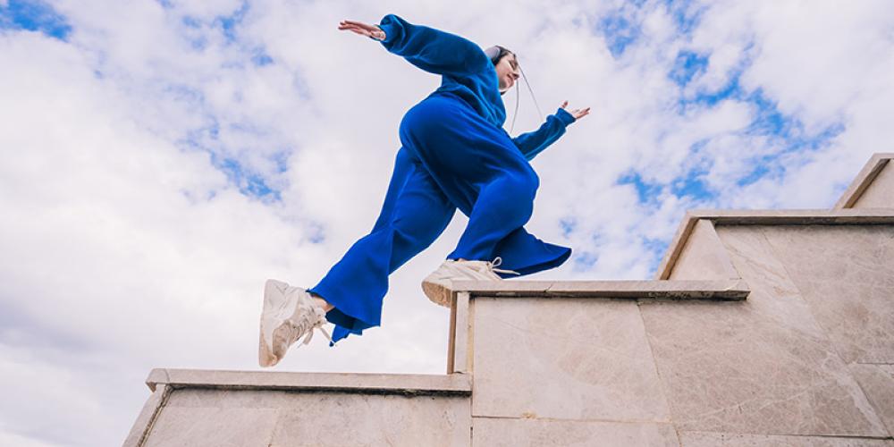 Frau in einem blauen Trainingsanzug läuft eine Treppe aufwärts