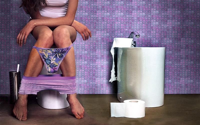 Frau sitzt auf der Toilette