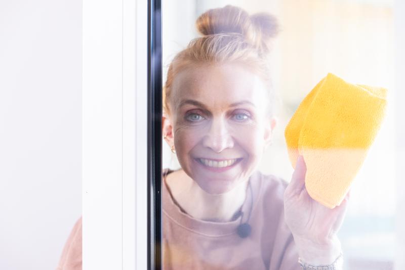 Frau putzt Fenster