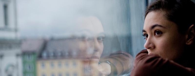 Frau in häuslicher Isolation schaut aus dem Fenster