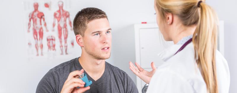 Asthmatiker mit Inhalator unterhält sich mit Ärztin